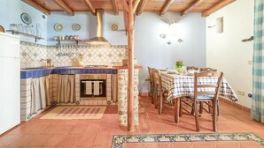 A kitchen with a tiled backsplash, wooden ceiling beams, and a dining area with a checkered tablecloth.