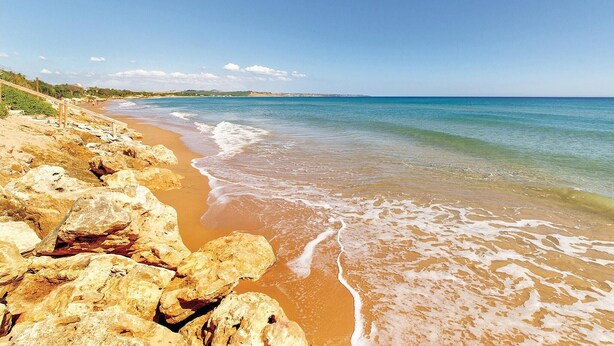 A beach with rocky shoreline and clear blue water.