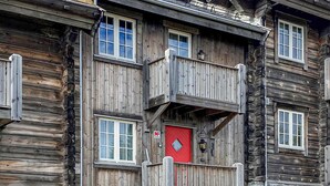 Ein mehrgeschossiges Holzgebäude mit Balkonen, einer roten Tür und einem Schild, das eine Schule anzeigt.
