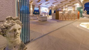 Un hall d’hôtel moderne doté d’un grand espace salon, d’un comptoir d’accueil et d’une sculpture en pierre.