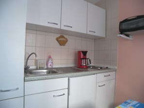 Eine Küche mit weißen Schränken, einer Granitabdeckung, einer roten Kaffeemaschine und einem Spülbecken.
