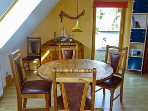 Ein Essbereich mit Holztisch und -stühlen, einer Hängelampe und einem Bücherregal.