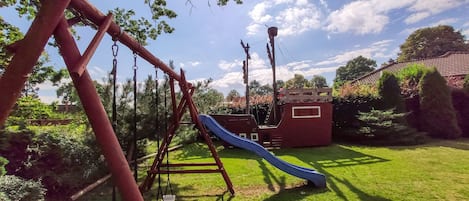 Ein Spielplatz mit Schaukeln, einer Rutsche und einer Klettervorrichtung.