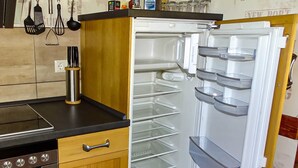 A kitchen with a built-in oven, a stainless steel range hood, and a double-door refrigerator with multiple shelves.