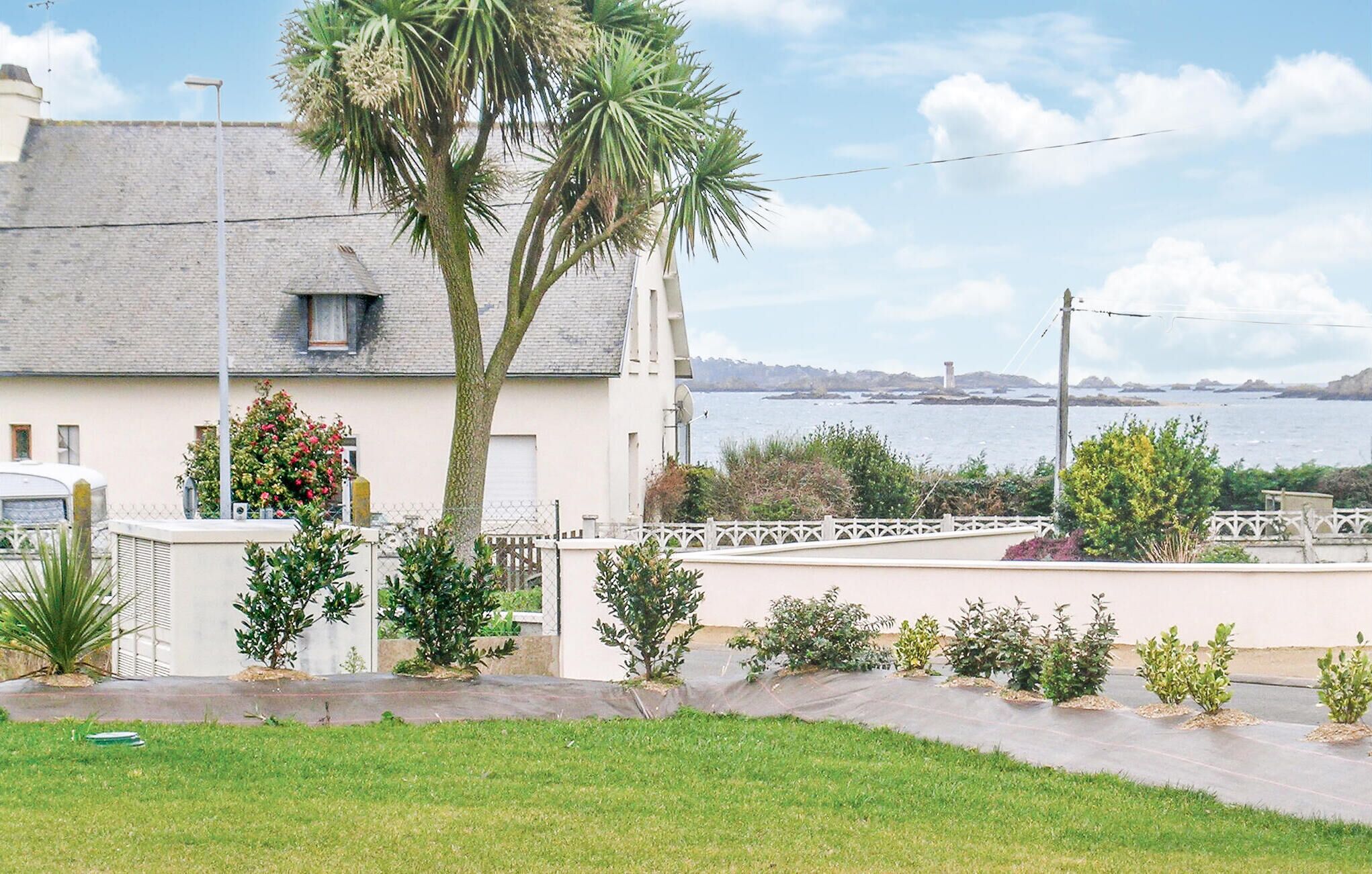 Una casa costera con fachada blanca, un balcón y vista al mar.