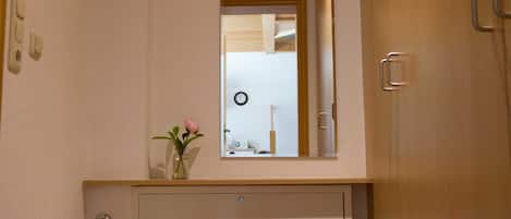 A bathroom with a white vanity, a small stool, a mirror, and a wall-mounted towel rack.