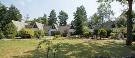 A row of modern, single-story cabins with pitched roofs, surrounded by well-maintained lawns and trees.