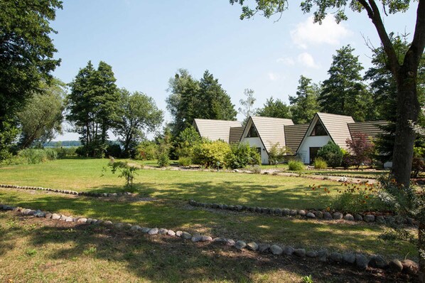 Une rangée de cabanes aux toits inclinés, entourées d’une pelouse bien entretenue et d’arbres.