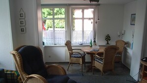 Un salon chaleureux, avec des meubles en osier, une table à manger et une fenêtre donnant sur un paysage verdoyant.