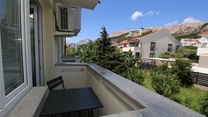 Varanda com mesa e cadeiras, vista para área residencial com casas e uma montanha ao fundo.