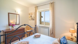 A bedroom with a bed, a chair, a dresser, a window with a view, and a lamp. - Beach front home in Ribera (AG) (Ribera (AG))