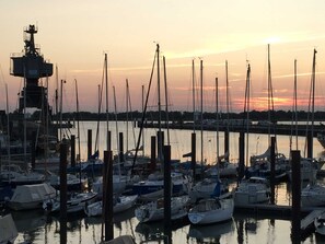 Ein Yachthafen mit mehreren Booten, die an hölzernen Stegen vor Sonnenuntergang liegen.