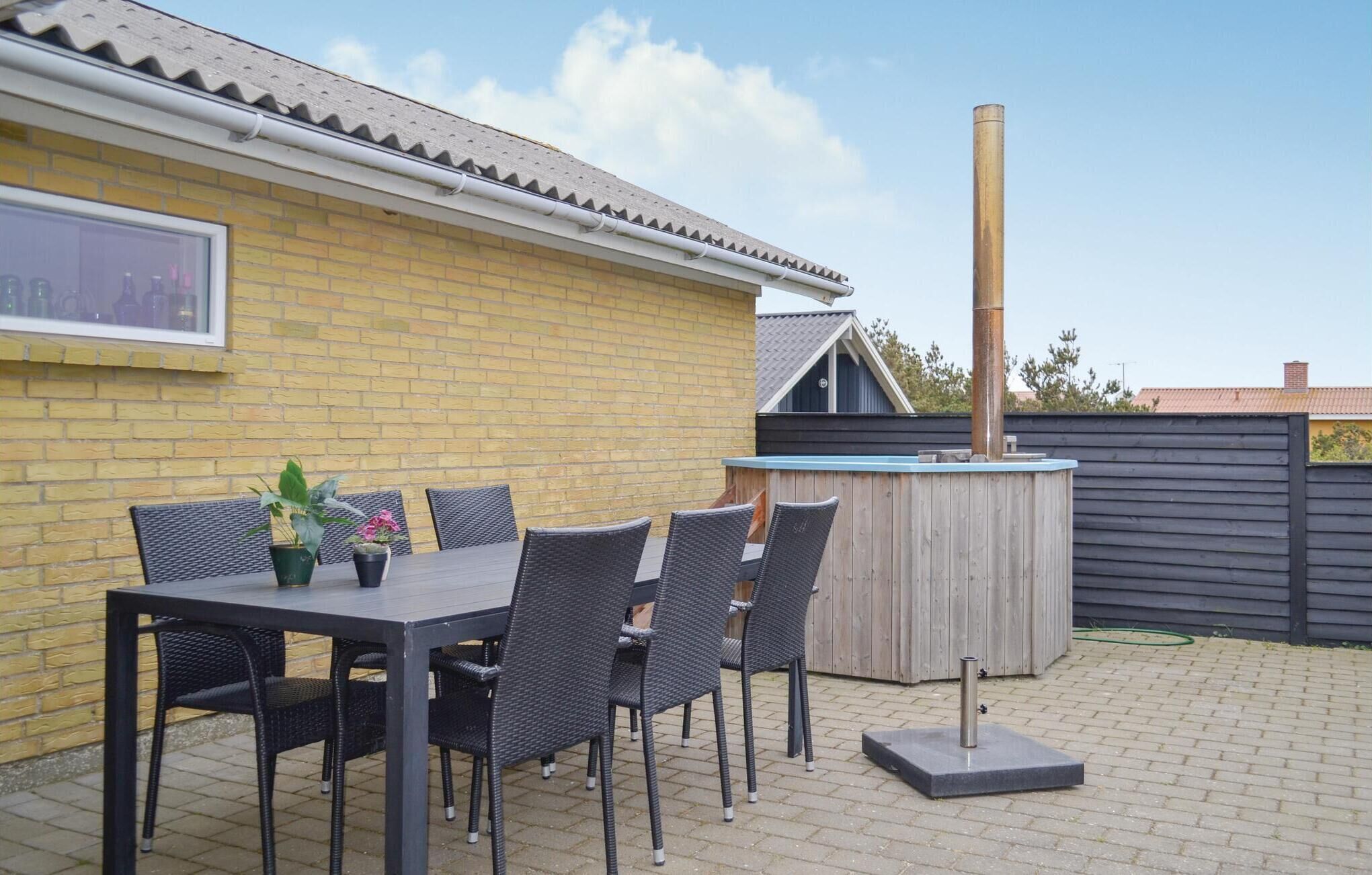 Une terrasse extérieure avec un mur en briques, une table avec des chaises et un poêle à bois.