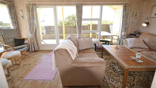 Un salon chaleureux avec un canapé beige, une table basse en bois et un fauteuil en osier.