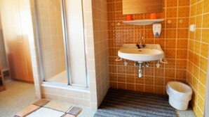 Een badkamer met douche, wastafel en toilet.