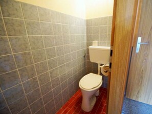 Une salle de bain avec des toilettes, un rouleau de papier toilette et un mur carrelé.