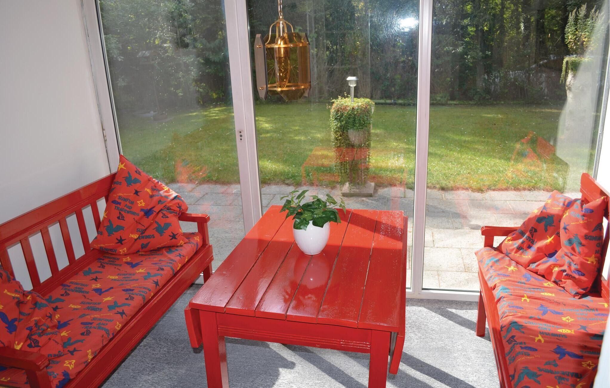 A room with a red sofa set, a wooden table, and a potted plant.