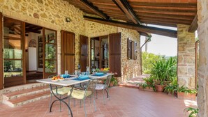 A stone building with a covered patio, a table set for dining, and potted plants. - 2 bedroom beautiful home in Massa Marittima GR (Massa Marittima GR)