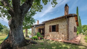 A stone house with a chimney, surrounded by a garden and a large tree. - 2 bedroom beautiful home in Massa Marittima GR (Massa Marittima GR)