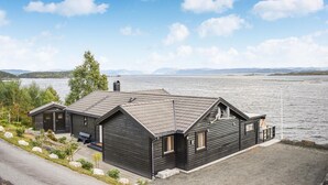 A cabin by a lake with a clear view of the water and distant mountains. - Nice home in Nedstrand with sauna (Nedstrand)