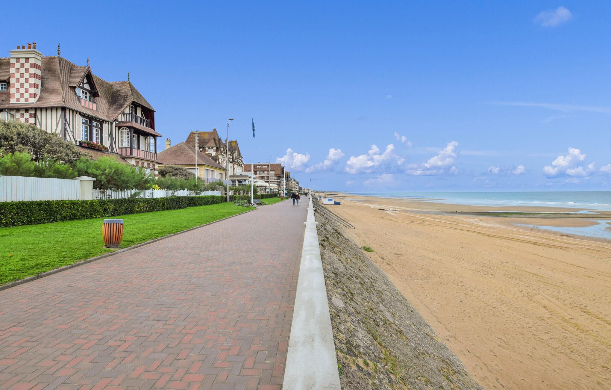 Ein Küstenweg mit traditioneller Architektur, der zu einem Sandstrand führt.