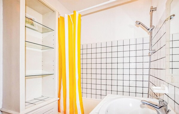 Ein Badezimmer mit einem weißen Waschbecken, einer Duschkabine aus Glas und einer gefliesten Wand.