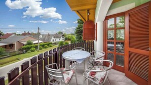 Un balcon avec une table et des chaises, une clôture en bois et une vue sur des maisons et de la verdure.