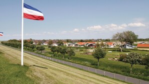 A residential area with houses, a flag, and a well-maintained lawn. - Friedrichskoog-Deichblick 7 (Friedrichskoog)