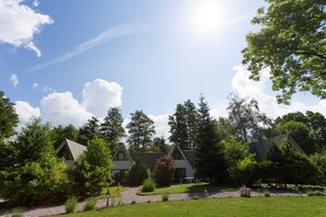 A building with a triangular roof, surrounded by trees and a well-maintained lawn.