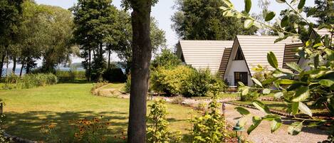 A house with a sloped roof, surrounded by a well-maintained garden with a variety of plants and a lawn.