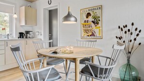 Eine moderne Küche mit Essbereich, ausgestattet mit einem runden Tisch, weißen Stühlen und einer Hängeleuchte.