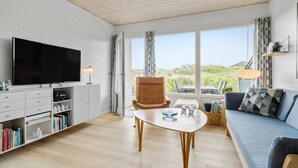 Ein modernes Wohnzimmer mit Flachbildfernseher, einer Couch, einem Couchtisch und einem Bücherregal.