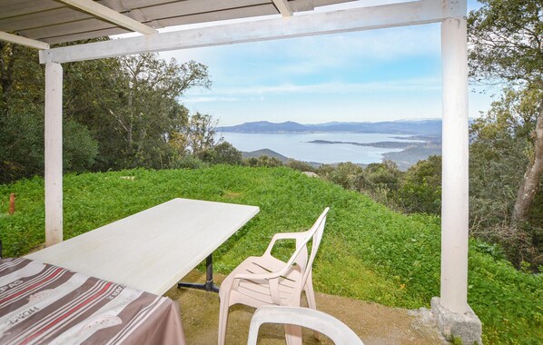 A covered outdoor seating area with a table and chairs, overlooking a scenic view of a body of water and distant mountains. - 1 bedroom cozy home in Coti Chiavari (Coti Chiavari)