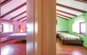 Cozy loft-style room with two separate sleeping areas, a window offering a view, and a unique sloped ceiling.