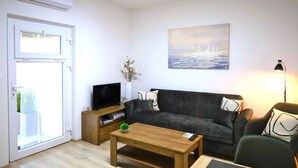 Una sala de estar con un sofá, una mesa de centro, un televisor y un cuadro en la pared.