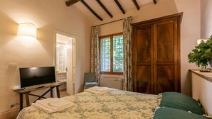 A bedroom with a bed, a TV, a window with curtains, and a plant. - 3 bedroom beautiful home in Ischia di Castro -VT- (Ischia di Castro -VT-)