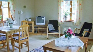 Ein gemütliches Wohnzimmer mit Holzmöbeln, einem Fernseher und Topfpflanzen.