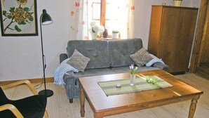 Ein Wohnzimmer mit grauem Sofa, einem Holztisch, einem schwarzen Sessel und einer Stehlampe.