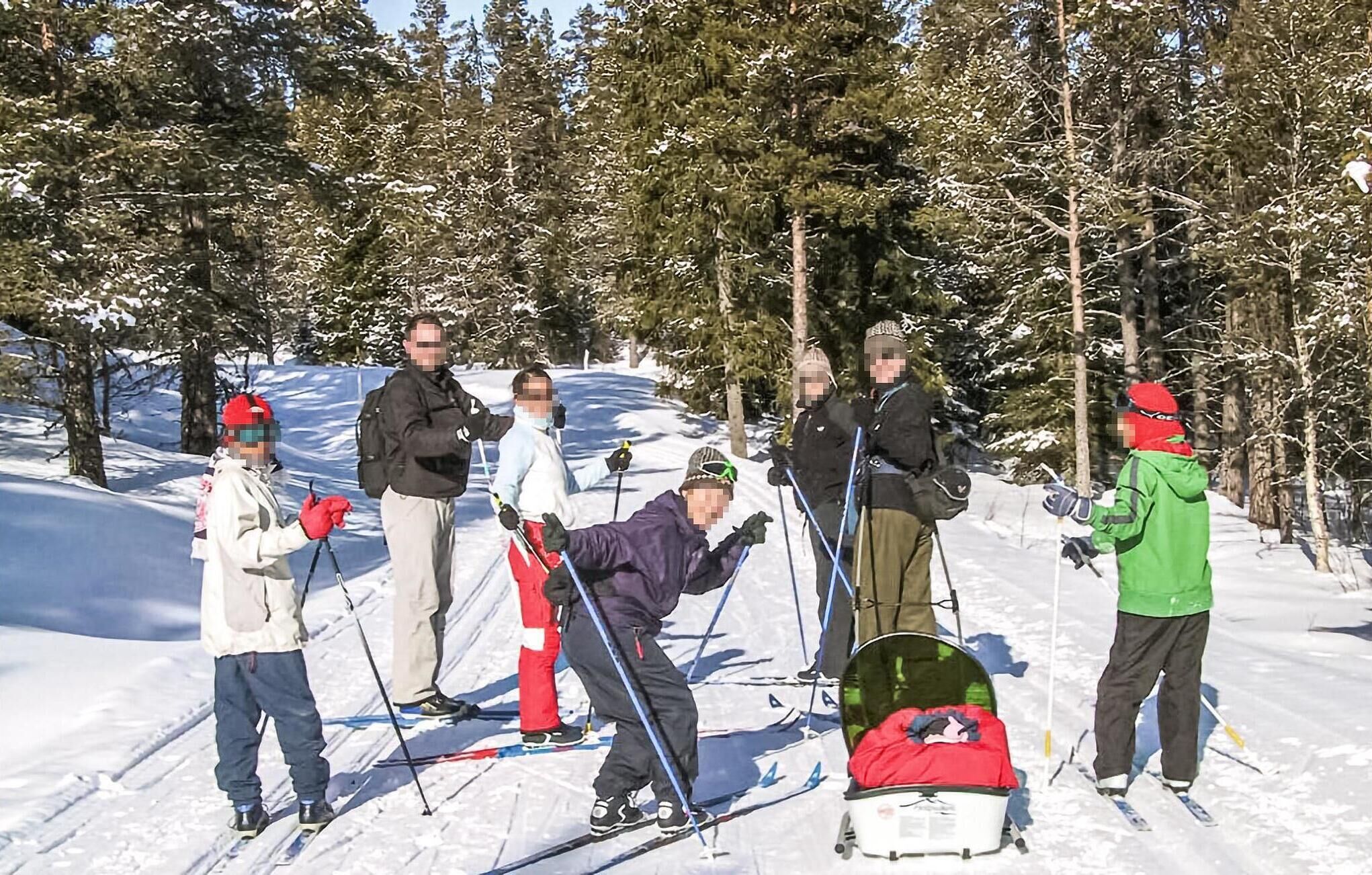 Un grupo de personas esquiando en una ladera nevada rodeada de árboles.