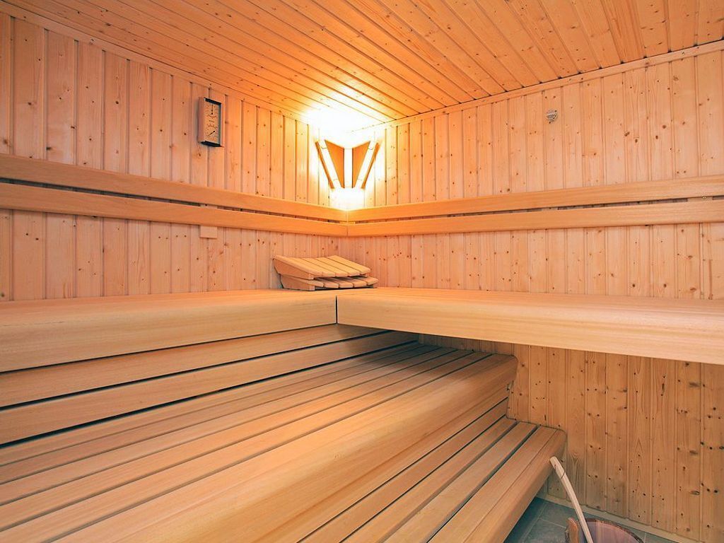 Una sauna con bancos de madera y un accesorio de luz central.