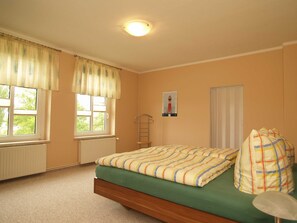 A bedroom with a bed, two windows, a radiator, a wall-mounted ladder, and a poster. - KR-07 - Karl-Risch-Str. 7 units. Above. (Kühlungsborn)