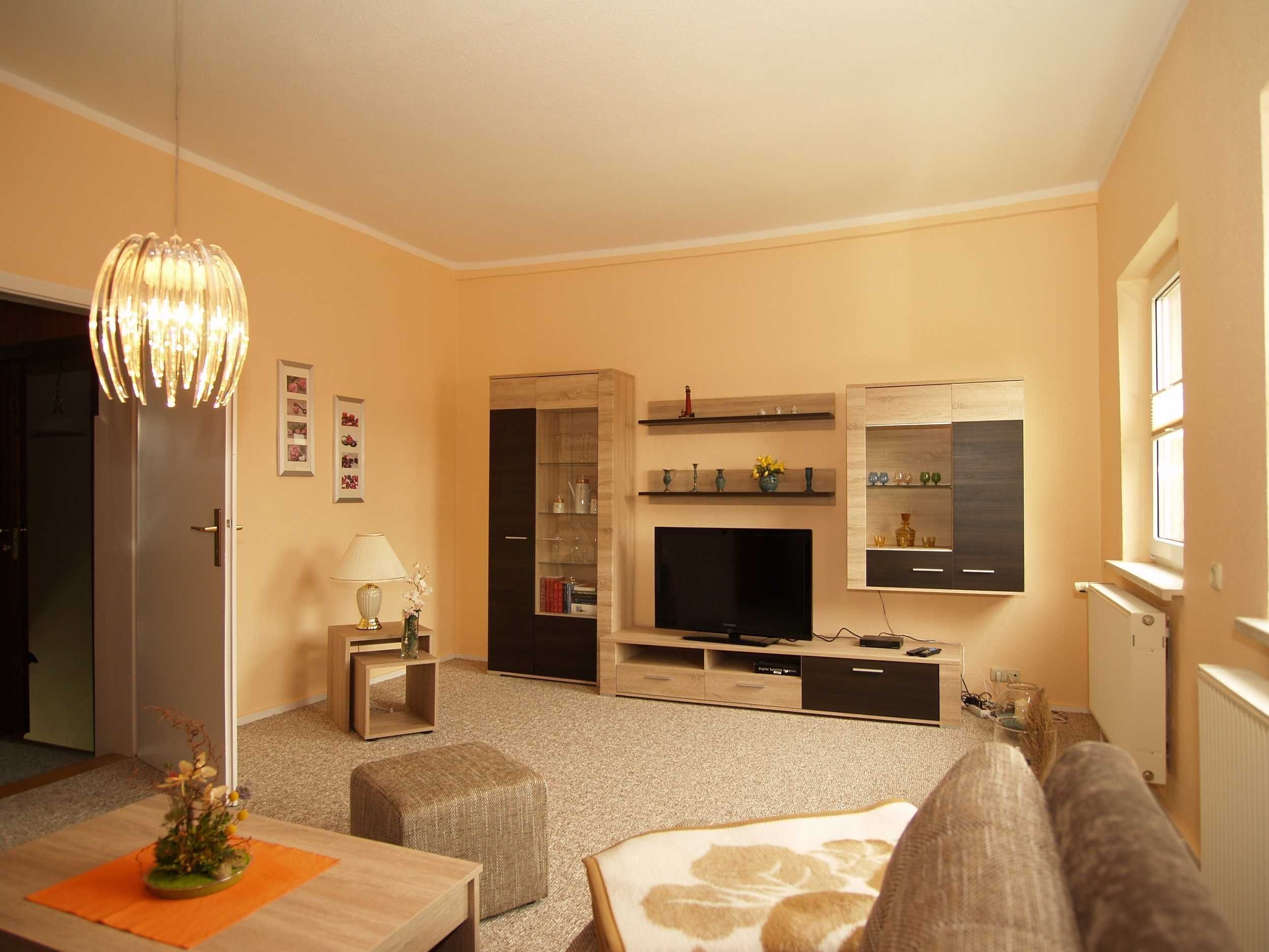 A modern living room with a flat-screen TV, wooden entertainment unit, and a cozy seating area.