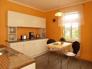 A compact kitchen with white cabinets, a coffee maker, and a table with chairs. - KR-07 - Karl-Risch-Str. 7 units. Above. (Kühlungsborn)