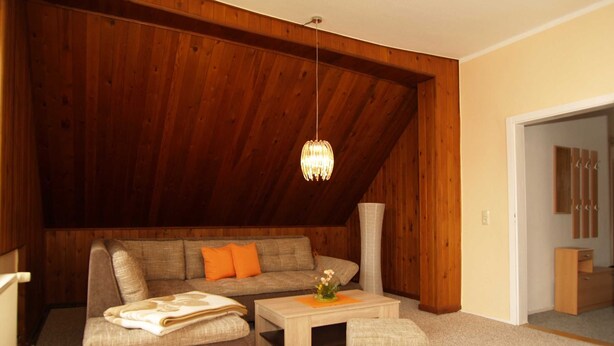 A cozy living room with a high ceiling, wooden paneling, a sofa, a coffee table, and a small ottoman. - KR-07 - Karl-Risch-Str. 7 units. Above. (Kühlungsborn)