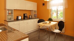 A compact kitchen with white cabinets, a coffee maker, and a table with chairs. - KR-07 - Karl-Risch-Str. 7 units. Above. (Kühlungsborn)