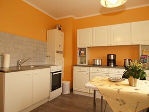 A compact kitchen with white cabinets, a sink, a stove, and a coffee maker. - KR-07 - Karl-Risch-Str. 7 units. Above. (Kühlungsborn)