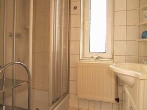 Une salle de bain avec une douche, un lavabo et une fenêtre.