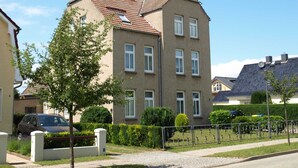 A multi-story residential building with a tiled roof, multiple windows, and a paved driveway. - KR-07 - Karl-Risch-Str. 7 units. Above. (Kühlungsborn)