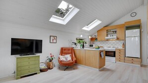 Eine moderne Küche mit einer zentralen Kochinsel, Holzschränken, einem Einbauofen und einem Kühlschrank.
