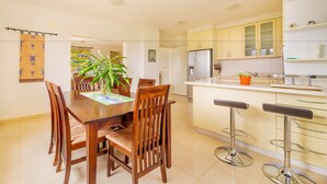 A modern kitchen with wooden chairs, a dining table, and a bar area with stools. - Kis Residence (Korcula)